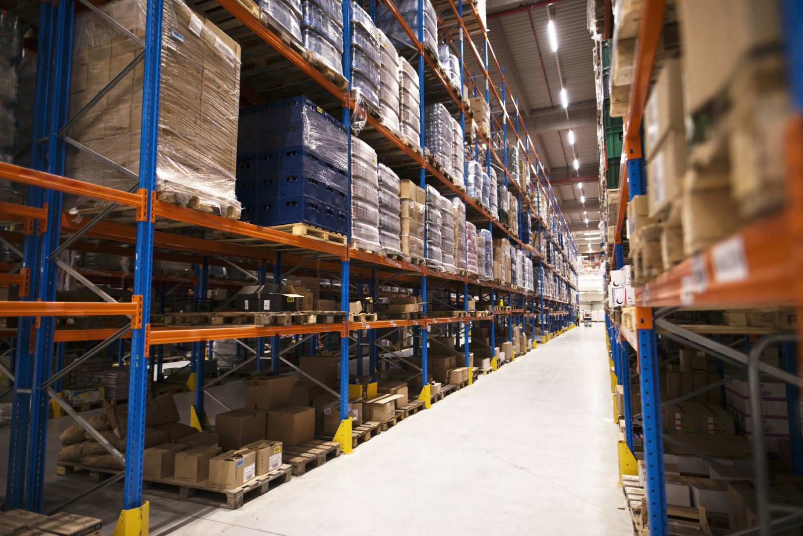 Interior of large distribution warehouse with shelves stacked with palettes and goods ready for the market.